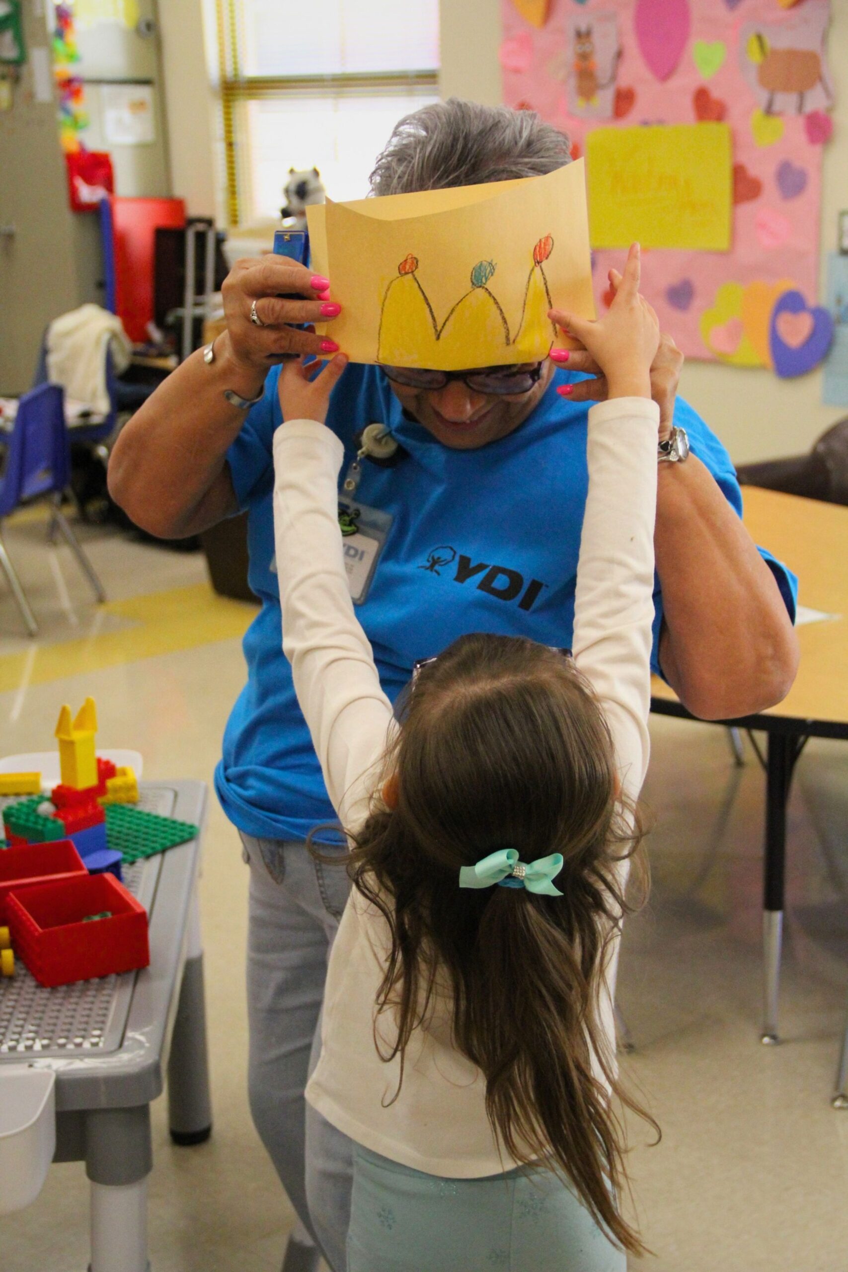 A YDI Head Start student puts a paper crown on her teacher in Artesia, New Mexico